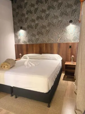 a bedroom with a large bed with a wooden headboard at Apartaestudios Zeni in Medellín