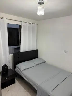 a bedroom with a bed and a window with white curtains at Apartamento céntrico y acogedor in Medellín