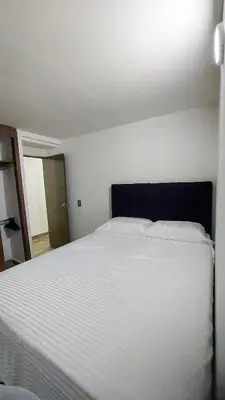 a bedroom with a large white bed with a black headboard at Laureles Estadio Lofts 33 in Medellín
