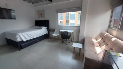 a bedroom with a bed and a couch and a table at Laureles Estadio Lofts 33 in Medellín