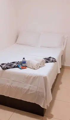 a white bed with a bottle of water on it at hotel chanel in Itagüí