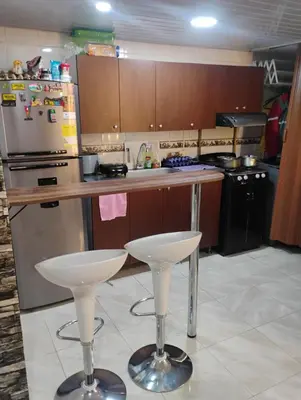 a kitchen with two bar stools and a refrigerator at Apto medellin in Medellín
