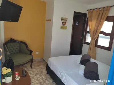 a room with two beds and a chair and a television at YoAmoJardín, Parejas, es como estar en casa in Jardin