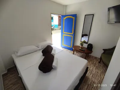 a bedroom with a white bed and a blue door at YoAmoJardín, Parejas, es como estar en casa in Jardin