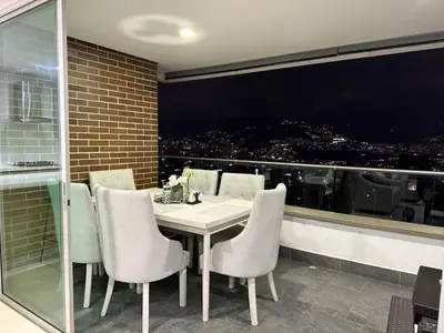 a dining room with a table and chairs with a view at Apartamento Deluxe poblado in Medellín