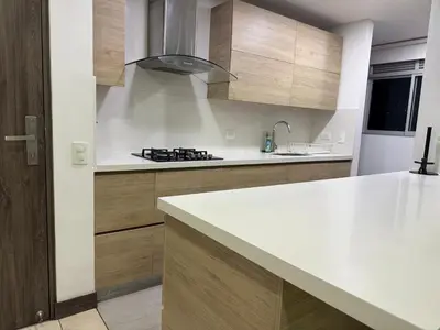 a kitchen with a white counter top and wooden cabinets at Apartamento Deluxe poblado in Medellín