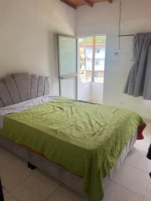 a bedroom with a bed with a green blanket on it at Home river in Itagüí