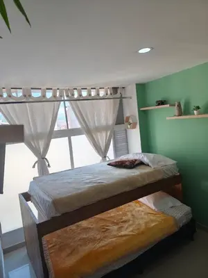 two beds in a room with a window at apartaestudio in Medellín