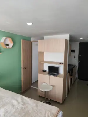 a bedroom with a bed and a desk with a laptop at apartaestudio in Medellín