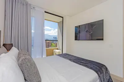 a white bedroom with a bed and a window at El Poblado Prime Location Medellin Apt in Medellín