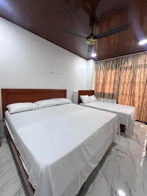 two beds in a bedroom with white sheets at Apartahotel María Antonia in Doradal