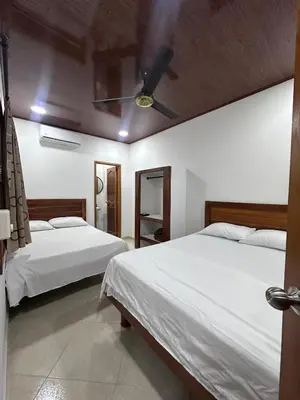 a bedroom with two beds and a ceiling fan at Apartahotel María Antonia in Doradal