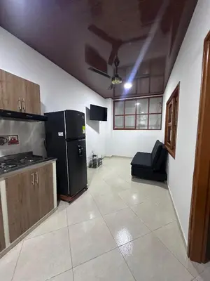a kitchen with a black refrigerator and a couch at Apartahotel María Antonia in Doradal