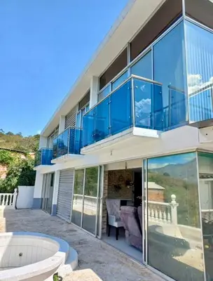 a large house with glass windows and a patio at Finca De Lujo En Copacabana Antioquia in Copacabana