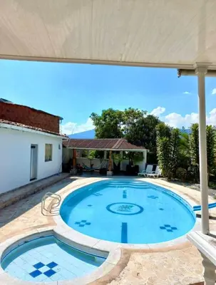 a large swimming pool in a patio with an umbrella at Finca De Lujo En Copacabana Antioquia in Copacabana