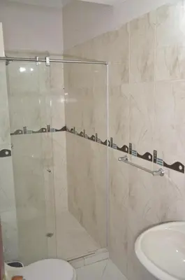 a shower with a glass door next to a sink at Apto Amoblado 3 Hab Cerca al Atanasio in Medellín
