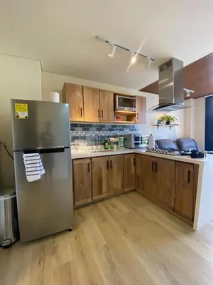 a kitchen with a stainless steel refrigerator and wooden cabinets at San Telmo Guatape Apto con Jacuzzy in Guatapé