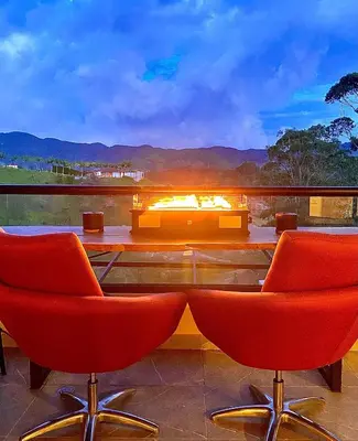 a living room with two red chairs and a fireplace at San Telmo Guatape Apto con Jacuzzy in Guatapé
