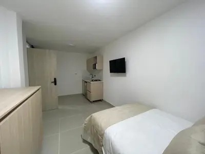 a white bedroom with a bed and a kitchen at Living Yellow in Alpujarra