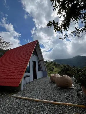 a small white building with a red roof and two large rocks at Kamalú Glamping in Medellín