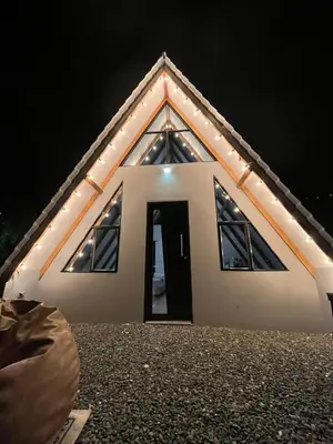 a small white house with a door in the night at Kamalú Glamping in Medellín