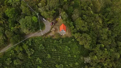 an aerial view of a red barn in the middle of a forest at Kamalú Glamping in Medellín