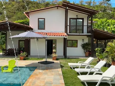 a villa with a pool and chairs and an umbrella at Finca en Sopetran con Piscina lnfinita y Jacuzzi in Sopetran