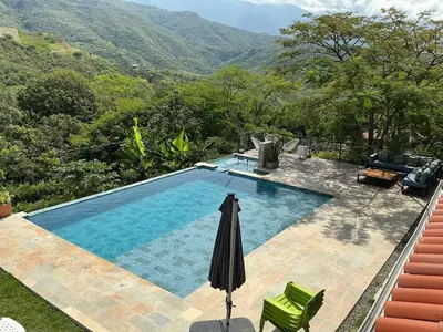 a swimming pool with an umbrella and chairs and mountains at Finca en Sopetran con Piscina lnfinita y Jacuzzi in Sopetran