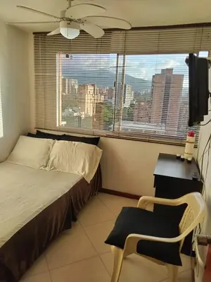 a bedroom with a bed and a chair and a window at Habitación en el poblado in Medellín