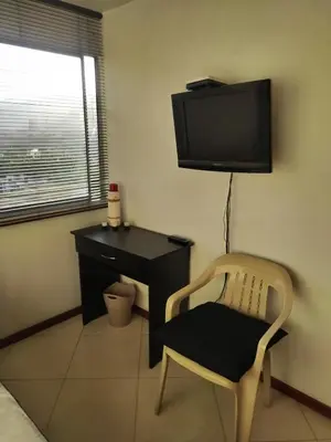 a room with a chair and a desk and a television at Habitación en el poblado in Medellín