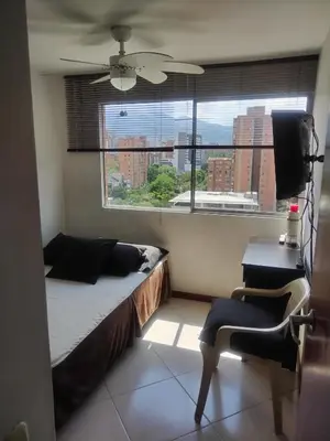 a bedroom with a bed and a desk and a window at Habitación en el poblado in Medellín