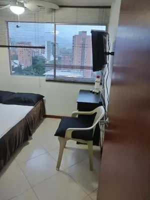 a room with a chair and a tv and a window at Habitación en el poblado in Medellín