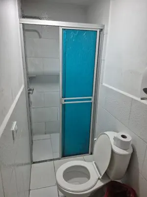 a bathroom with a toilet with a glass shower door at Hotel bastilla real in Medellín