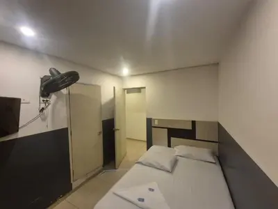 a bedroom with a bed and a fan on the wall at Hotel bastilla real in Medellín