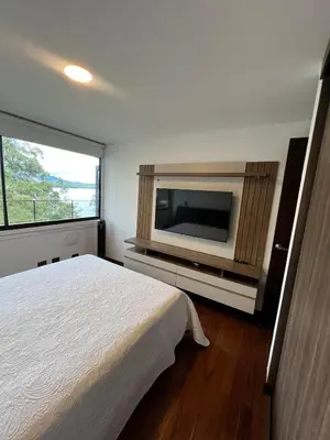 a bedroom with a bed and a flat screen tv at Cabaña en Guatapé in Guatapé