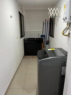 a laundry room with a trash can and a machine at Spacious and bright in Medellín