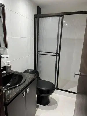 a bathroom with a black toilet and a sink at Spacious and bright in Medellín