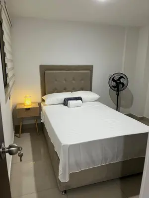 a bedroom with a large bed with white sheets at Spacious and bright in Medellín