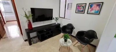 a living room with two black chairs and a television at Balsos de oviedo in Medellín