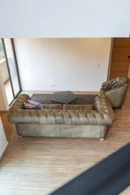 a leather couch in a living room with a person sitting on it at Duplex First laureles park in Medellín