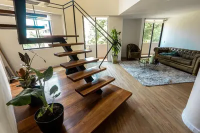 a living room with a spiral staircase in a house at Duplex First laureles park in Medellín