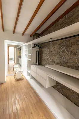 a room with a wall with shelves and a tv at Duplex First laureles park in Medellín