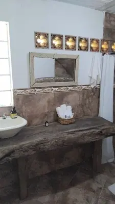 a bathroom with a wooden bench with a sink and a mirror at El Palmar Lodge in Chiquinquirá