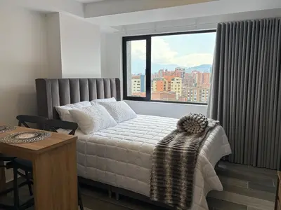 a bedroom with a bed and a large window at Apartamento Laureles in Medellín
