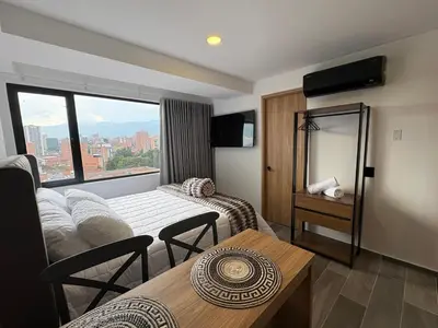 a hotel room with a bed and a table and a window at Apartamento Laureles in Medellín