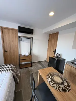 a room with a bed and a table and a kitchen at Apartamento Laureles in Medellín