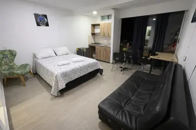 a bedroom with a bed and a couch and a kitchen at Loft con balcón y baño Laureles Belén TOP LOCATION in Medellín