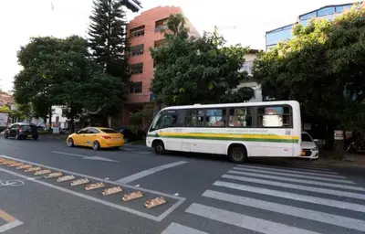 a white bus driving down a street with a taxi at Loft con balcón y baño Laureles Belén TOP LOCATION in Medellín