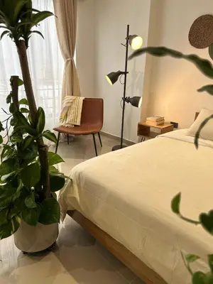 a bedroom with a bed and a chair and a plant at Boho Green Apartment in Medellín
