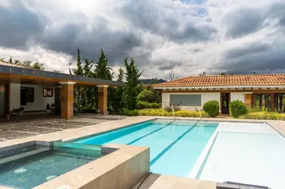 a swimming pool in front of a house at Mansión de lujo La Reina Llanogrande in Rionegro